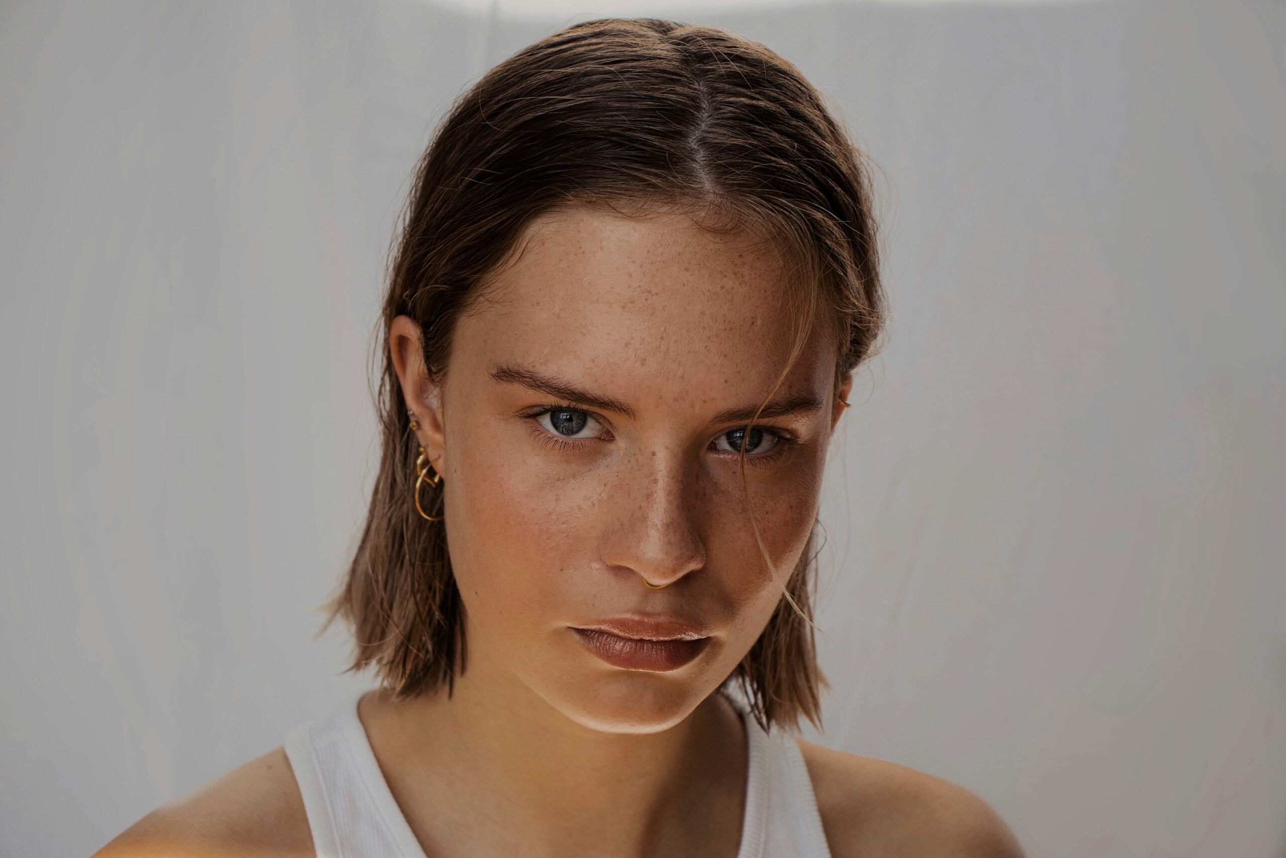 Close-up portrait of a confident young woman with natural freckles and minimal makeup, symbolizing clean, natural, chemical-free cosmetics